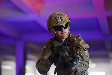 Image showing A professional soldier undertakes a perilous mission in an abandoned building illuminated by neon blue and purple lights