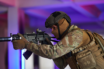 Image showing A professional soldier undertakes a perilous mission in an abandoned building illuminated by neon blue and purple lights