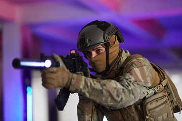 Image showing A professional soldier undertakes a perilous mission in an abandoned building illuminated by neon blue and purple lights