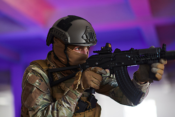 Image showing A professional soldier undertakes a perilous mission in an abandoned building illuminated by neon blue and purple lights