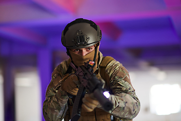 Image showing A professional soldier undertakes a perilous mission in an abandoned building illuminated by neon blue and purple lights