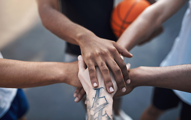 Image showing Lets go team. Closeup shot of a group of sporty young men joining their hands together in a huddle on a sports court.