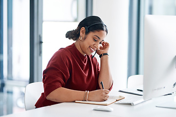 Image showing Shes always there to help. a young businesswoman wearing a headset while writing notes in an office.