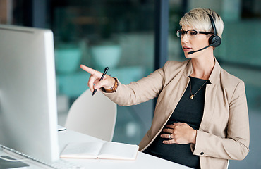 Image showing Shell come up with a solution that works. a pregnant businesswoman wearing a headset while working on a computer in an office.