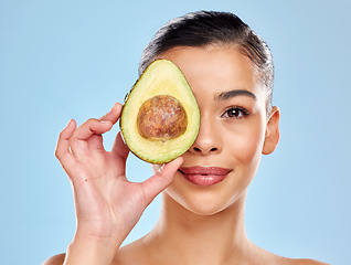 Image showing The natural oils in avocados penetrate the skin to nourish and hydrate. Studio portrait of an attractive young woman posing with an avocado against a blue background.
