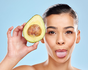 Image showing This is how I glow. Studio portrait of an attractive young woman sticking out her tongue while posing with an avocado against a blue background.