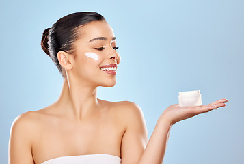 Image showing Good product choices are good investments. Studio shot of an attractive young woman holding a beauty product against a blue background.