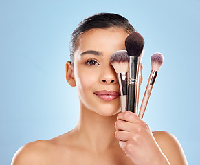 Image showing Create magic with your wand. Studio portrait of an attractive young woman holding a collection of makeup brushes against a blue background.