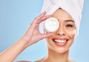 Image showing She lights up the room with her glow. Studio portrait of an attractive young woman holding a beauty product against a blue background.