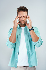 Image showing Im not in the mood to think right now. Studio shot of a young man with an uncomfortable facial expression due to a headache while standing against a grey background.