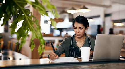 Image showing The hard work behind a successful side hustle. a young woman using a laptop and going over paperwork while working in a cafe.