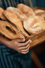 Image showing Wheres some butter when you need it. a woman holding a selection of freshly baked breads in her bakery.