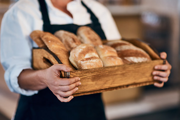 Image showing Baked by the head baker herself. a woman holding a selection of freshly baked breads in her bakery.