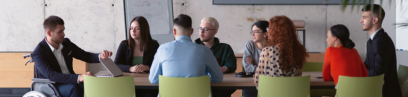 Image showing Wide crop photo of a diverse group of business professionals, including an person with a disability, gathered at a modern office for a productive and inclusive meeting.