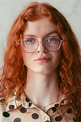 Image showing A young entrepreneur with captivating orange hair is striking a confident pose in front of a stylish gray wall.