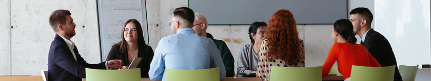 Image showing Wide crop photo of a diverse group of business professionals gathered at a modern office for a productive and inclusive meeting