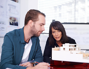 Image showing I think it looks great. Two architects in working on a model of a house.