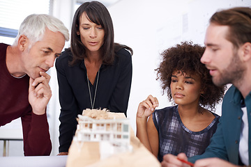 Image showing Contemplating his teams design. a group of architects working together on building plans.