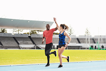 Image showing Well done. Full length shot of two young athletes high fiving while running along the track.