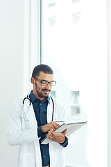 Image showing Determining the cause of his patients condition. a young doctor using a digital tablet in a modern hospital.