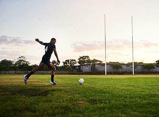 Image showing Practice makes perfect. Full length shot of a handsome young sportsman kicking a rugby ball during an early morning training session.