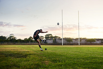 Image showing I never quit trying. Full length shot of a handsome young sportsman kicking a rugby ball during an early morning training session.