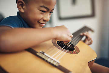 Image showing My friends love sports but I love playing the guitar. a young boy playing the guitar at home.