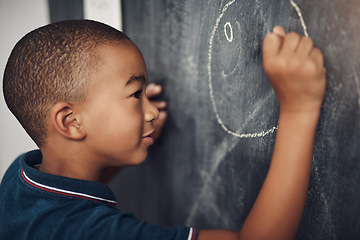 Image showing The only limits are the limits of their imagination. a young boy writing on a blackboard at home.