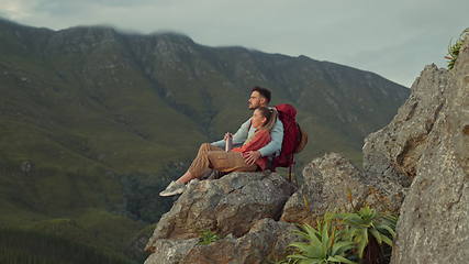 Image showing Hiking, mountain and view, couple relax on outdoor adventure travel and peace in nature with romance. Trekking, rock climbing and love, man and woman in natural environment sitting on cliff together.