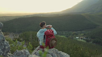 Image showing Hiking, mountain and man with backpack, water bottle and relax on outdoor adventure with freedom in nature. Trekking, rock climbing and hiker sitting for drink break, horizon and motivation with view