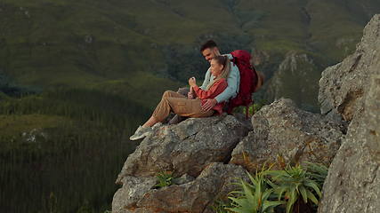 Image showing Hiking, mountain and love, couple relax on outdoor adventure and peace in nature with romance. Trekking, rock climbing and view, man and woman with view of natural landscape sitting on cliff together