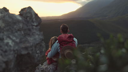 Image showing Hiking, mountain and sunrise, couple relax on outdoor adventure and peace in nature with romance from back. Trekking, rock climbing and love, man and woman with sunset horizon view on cliff together.