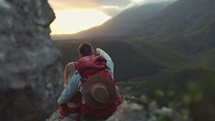 Image showing Hiking, mountain and view, couple relax on outdoor adventure and peace in nature with romance from back. Trekking, rock climbing and love, man and woman with sunset horizon sitting on cliff together.