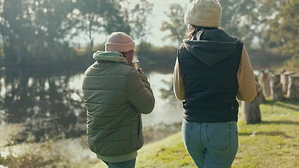 Image showing Talking, back and couple walking in nature with coffee while camping for vacation. Morning conversation, winter and a man and woman speaking while on a walk in a park for a holiday with tea together