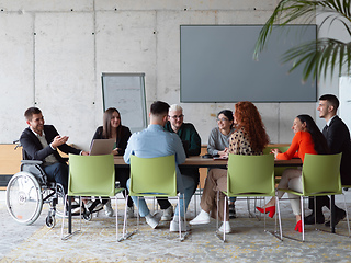 Image showing A diverse group of business professionals, including an person with a disability, gathered at a modern office for a productive and inclusive meeting.