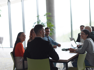 Image showing A diverse group of business professionals, including an person with a disability, gathered at a modern office for a productive and inclusive meeting.