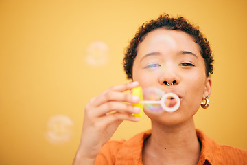 Image showing Portrait, blowing bubbles and woman in studio for fun, playful or freedom of expression on yellow background. Bubble, stress relief and face of lady model with liquid soap for celebration or weekend