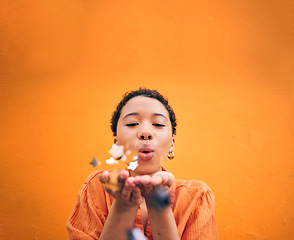 Image showing Blowing, petals and face of woman on orange background for natural beauty, skincare and romance. Flowers, happy and female person with floral confetti for cosmetics, makeup and satisfaction in studio