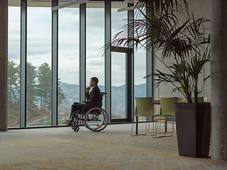 Image showing A melancholic businessman in a wheelchair sitting with a sad expression, gazing through the window of a modern office, conveying a sense of solitude