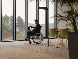 Image showing A businessman with disability in a wheelchair using laptop in a modern office