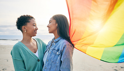 Image showing Lesbian couple, pride flag and freedom hug at beach for romance, happy or care in nature. Rainbow, love and women at the ocean embrace lgbt, gay or partner pride, date or romantic relationship moment