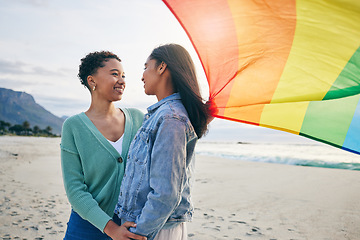 Image showing Gay, flag and lesbian couple at the beach for travel, freedom and bond, care and happy in nature together. Rainbow, love and women on ocean vacation embrace lgbt, partner or pride, date or acceptance