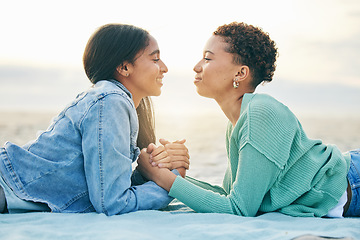 Image showing Love, ocean and sunset, lesbian couple on blanket together, holding hands on sand and holiday adventure. Lgbt women, bonding and relax on beach vacation with romance, pride and happy lying in nature.