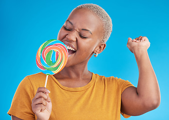 Image showing Lollipop, singing and a woman with candy in studio for sweets, rainbow and creative advertising. Happy black female person isolated on a blue background with sugar, freedom and happiness or color