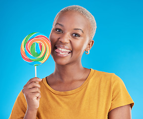 Image showing Lollipop, portrait and a woman with candy in studio for sweets, rainbow and creative advertising. Happy black female person isolated on a blue background with sugar, freedom or happiness and tongue