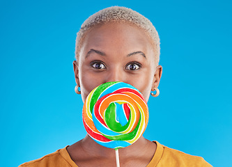 Image showing Candy, lollipop and portrait a woman in studio for wow sweets, rainbow and creative advertising. Happy black female person isolated on a blue background with sugar, freedom and color surprise