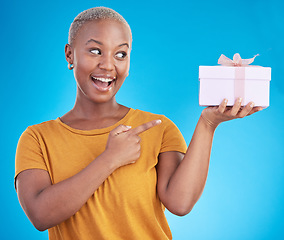 Image showing Gift, excited black woman and pointing at box in studio isolated on a blue background. Promotion, happy or African person with present for party, celebration of holiday or birthday for giveaway prize