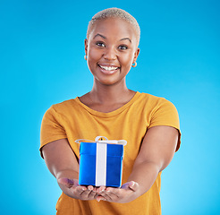 Image showing Portrait, gift and happy black woman with giveaway in studio isolated on a blue background. Face, giving and person with present box for party, celebration or birthday package for offer of donation