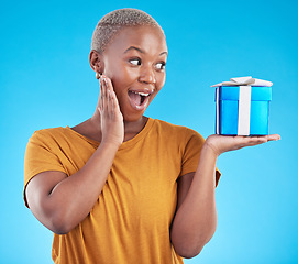 Image showing Wow, gift and excited black woman with box in studio isolated on a blue background. Surprise, happy and African person with present for party, celebration of holiday or birthday package for giveaway