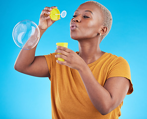 Image showing African, woman and blowing bubbles in studio, blue background or fun party celebration with liquid soap or toy. African girl, person and relax with happy, joyful or creative bubble for calm break